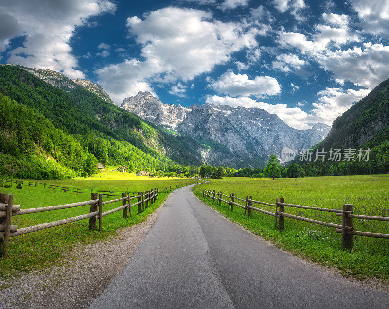 斯洛文尼亚洛加尔山谷，高山中的乡村公路，木栅栏，绿色的草地，夏季的树木。国家的道路。五彩缤纷的风景，有道路，岩石，田野，草地，日落时的蓝天和云彩