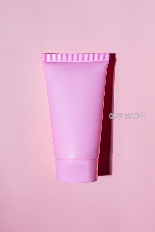 粉色挤压瓶塑料管的模型，用于药品或化妆品的品牌-面霜，凝胶，护肤品，牙膏。化妆品瓶容器上的白色背景与阴影。极简主义