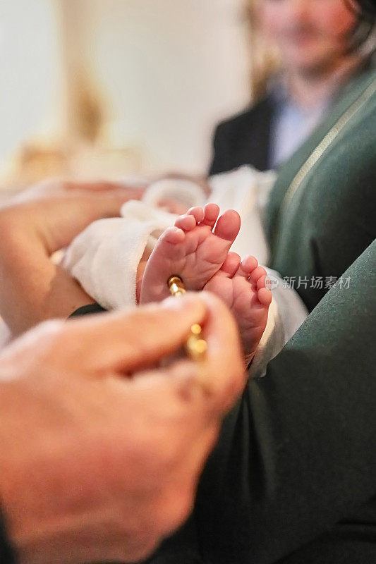 牧师在新生儿的脚上进行涂油仪式。