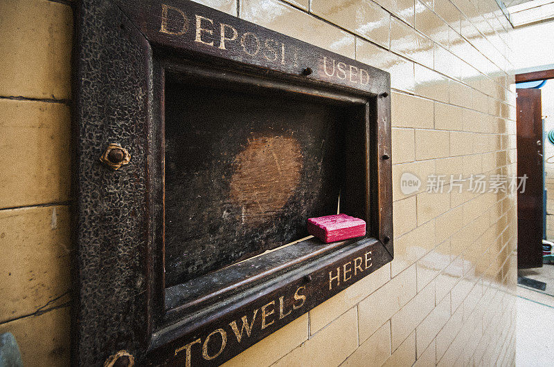 一个古老的维多利亚公共浴场游泳池的木制舱口“存放用过的毛巾”，上面有一块红色的石炭肥皂。
