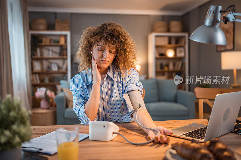 厌倦了互联网工作的年轻白人女性坐在家里的办公桌前测量血压