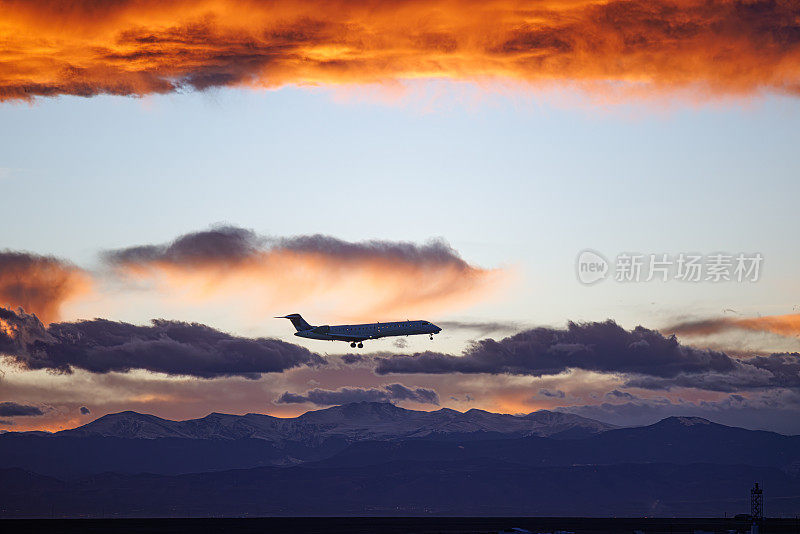 航空公司在日落时降落的飞机，背景是壮观的云和山脉