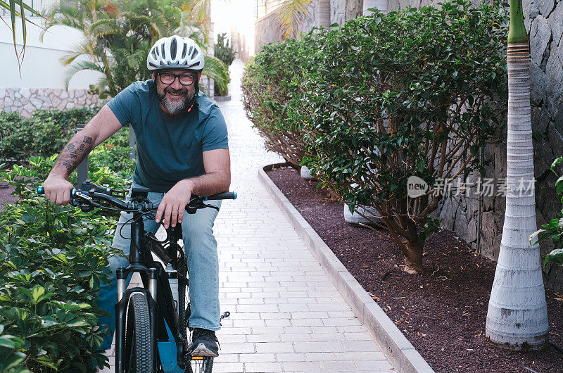 周末活动时戴着头盔骑电动自行车的人微笑无忧无虑的前视图，看着镜头，健康的运动生活方式理念