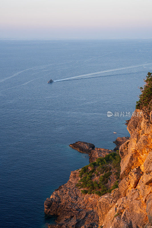 日落时分，索勒港美丽的岩石海岸，一艘孤独的游艇匆匆驶向港口。西班牙巴利阿里群岛马略卡岛