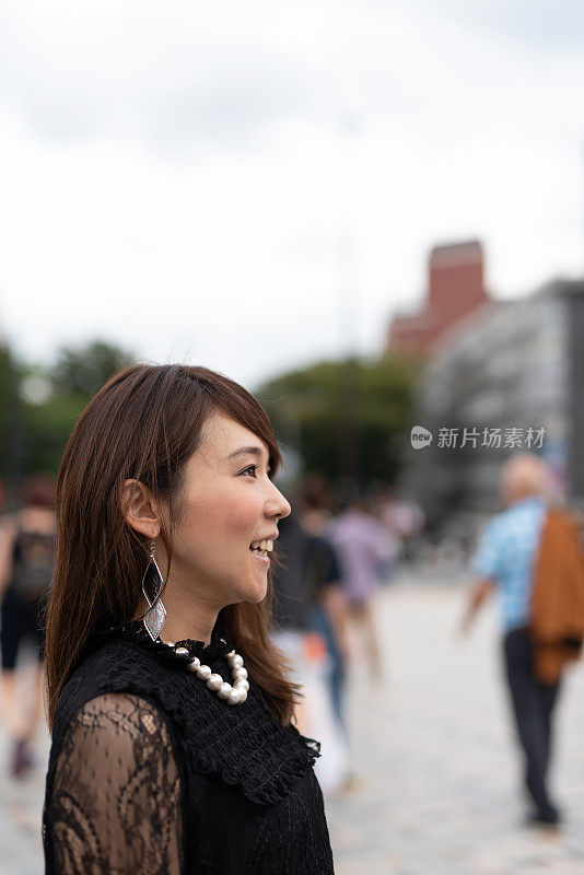 一名女子走在原宿车站附近的街道上，原宿是日本著名的观光胜地