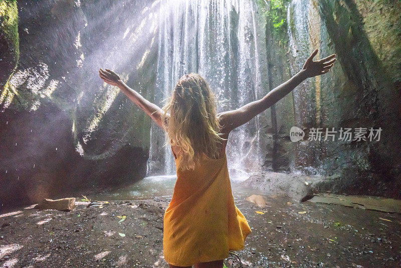 在巴厘岛的热带雨林中，旅行的年轻女子张开双臂拥抱大自然的美丽。人们以自然为旅游理念。