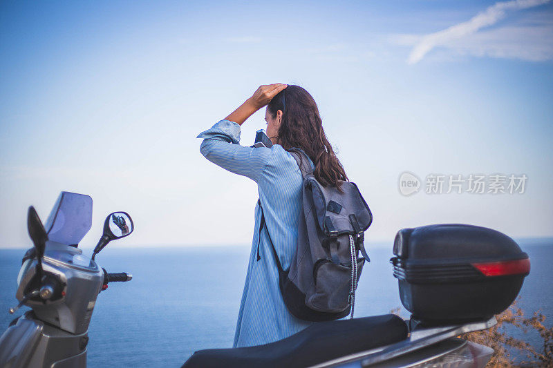 女孩骑着摩托车欣赏海景