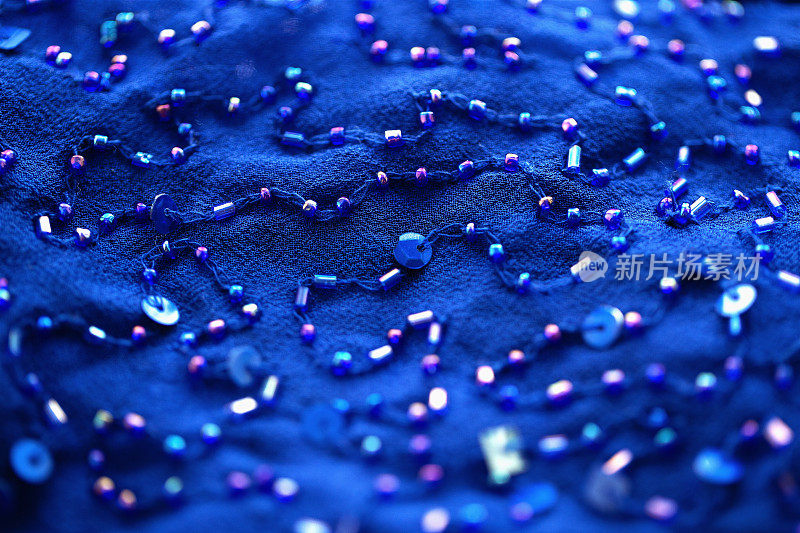 蓝色纺织品背景上的亮片和喇叭