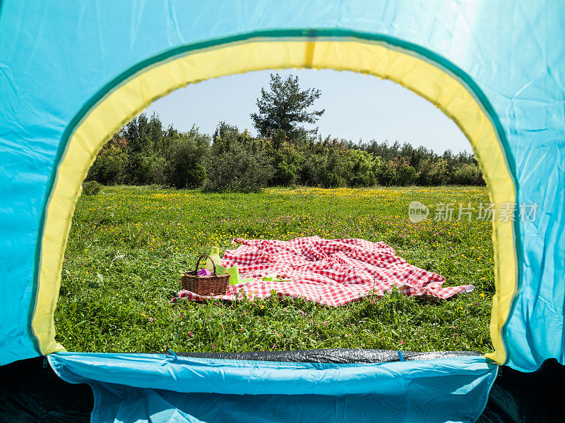 绿松石色的露营帐篷和红色的野餐毯在自然界