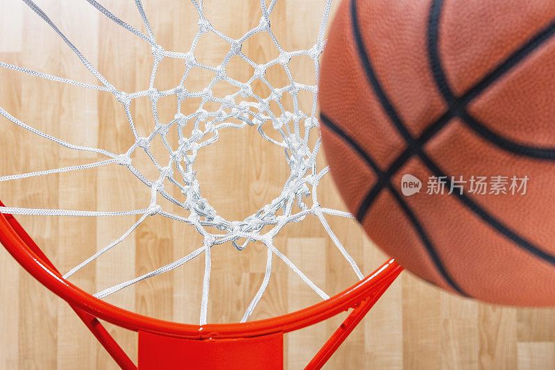 俯视着篮球网，球几乎就在网中，背景是竞技场的木地板