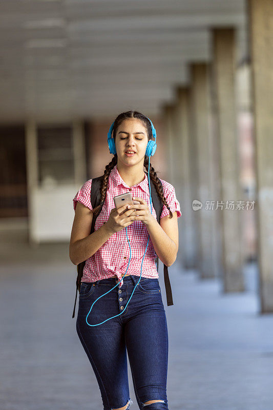 少女走在街上听着音乐