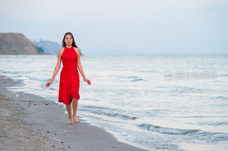 穿红衣服的年轻女子在海滩上跑步