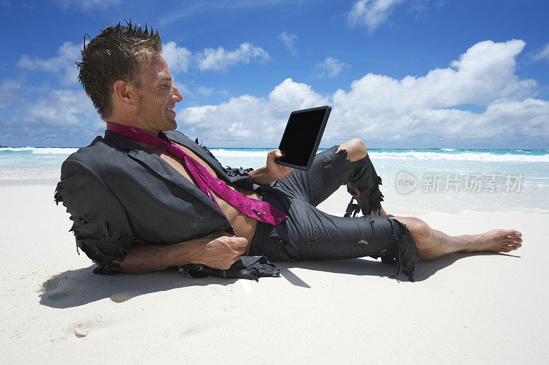 旅者漂流商人在海滩上用数字平板电脑放松