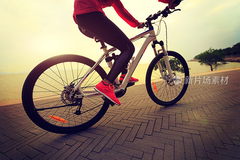 健康的生活方式年轻女子骑自行车在海边