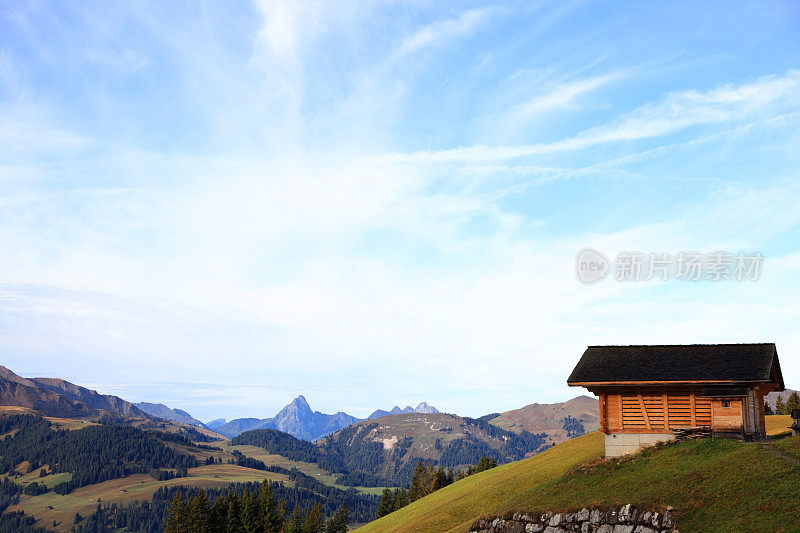 阳光明媚的瑞士阿尔卑斯山上的小山、天空和木屋