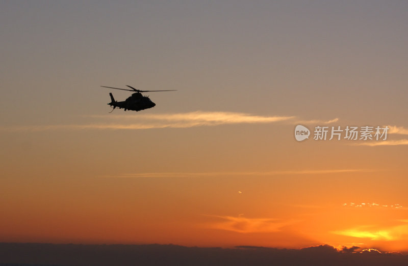 一架轮廓分明的直升机飞向冉冉升起的太阳