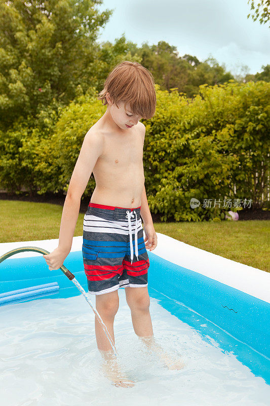 小男孩用软管给游泳池注水