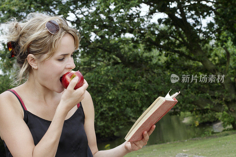 户外女孩拿着红苹果在户外看书