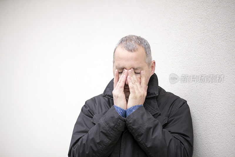 头发灰白的男人用双手遮住脸