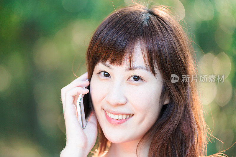 年轻漂亮的亚洲女人在用智能手机聊天