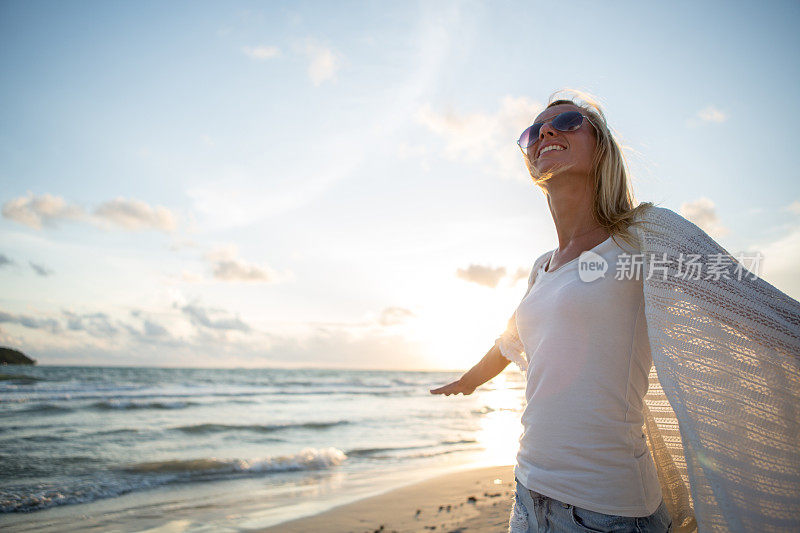 活泼的女孩欣赏日落时的海滩