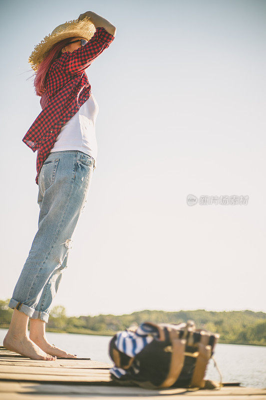 美丽的女人站在户外湖边的木码头上