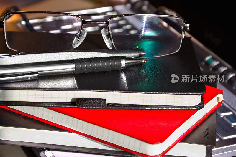 带笔和眼镜的笔记本放在电脑上