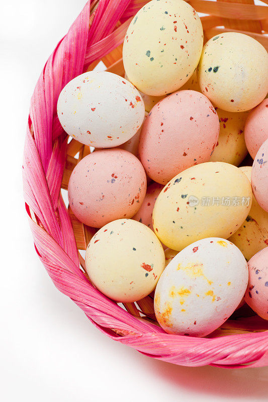 粉红色篮子里的点缀着糖衣的迷你复活节彩蛋