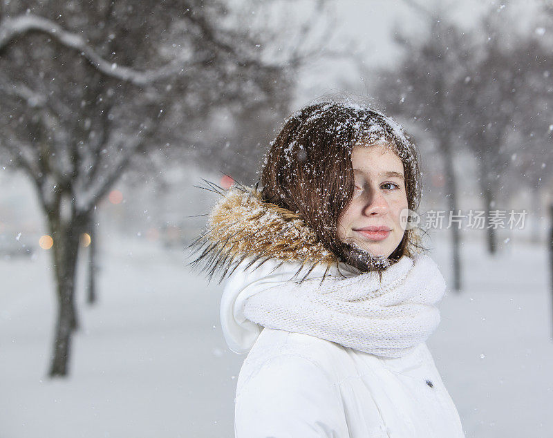 雪下穿着白色夹克的漂亮少女