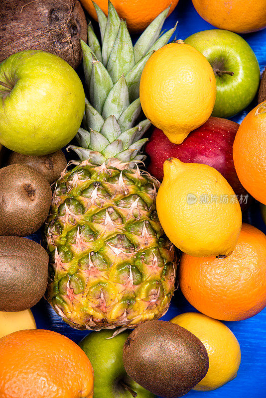 菠萝，葡萄柚，椰子，猕猴桃，橙子，香蕉，苹果放在蓝木板上