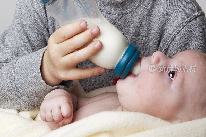 幼儿用奶瓶喂养2个月大的婴儿