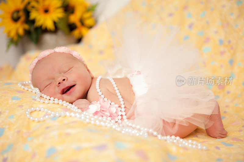 微笑的新生女婴戴着粉色的发带和珍珠
