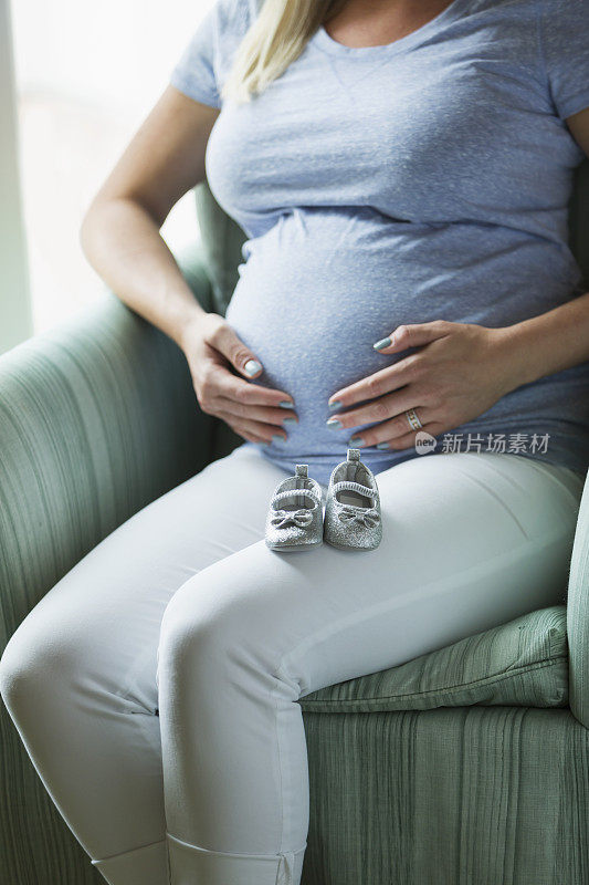 准妈妈，大腿上放着婴儿鞋