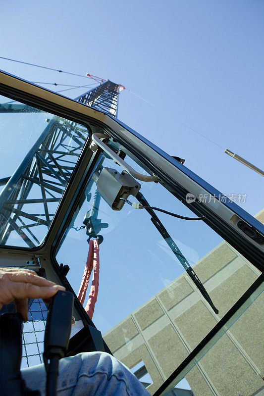 起重机操作员在商业建筑工地吊起新的屋顶梁