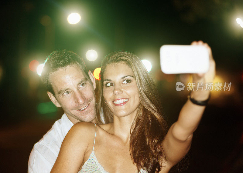 英俊的年轻夫妇在闪烁的灯光下微笑自拍