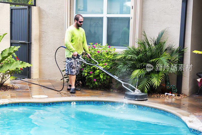 白人男性工人动力清洗住宅游泳池庭院瓷砖