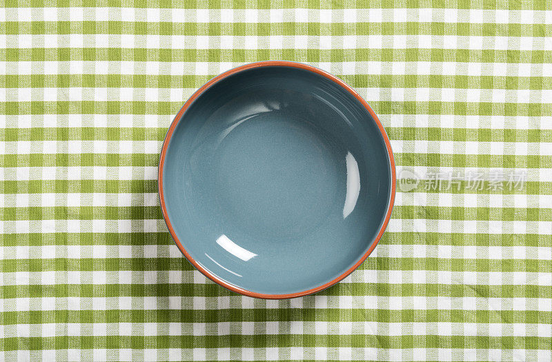 铺着绿色台布的桌子上空着一只陶瓷碗