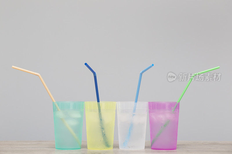 色彩鲜艳的杯子里装着清凉的冷水，并配有吸管。复制空间组成。