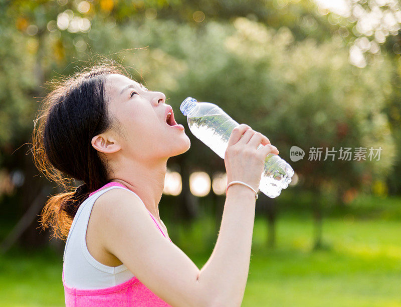 年轻女子在公园喝瓶装水
