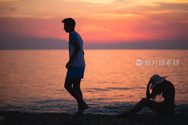 日落时分，一对情侣在海滩上剪影分手