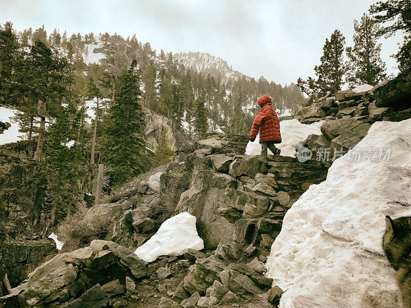 一个小男孩穿着他父亲的大衣爬上陡峭的山路