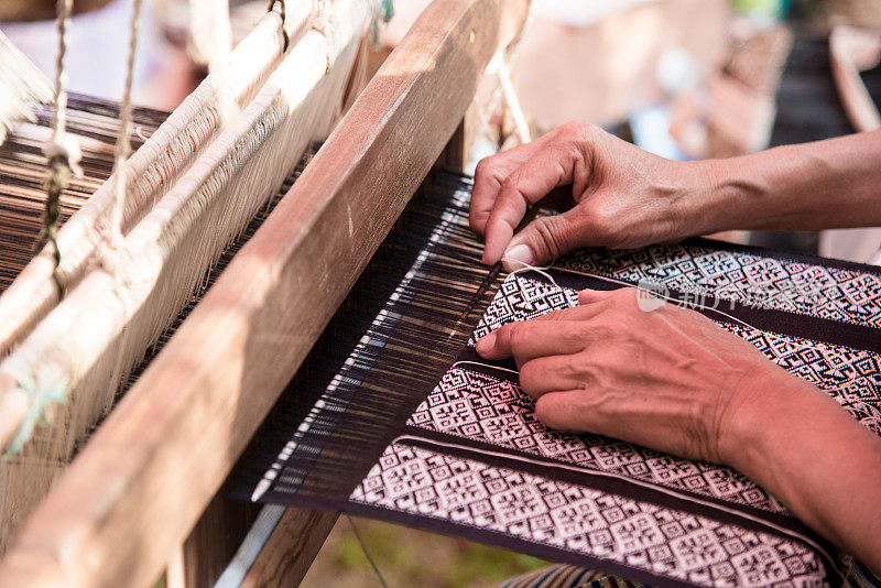 织工正在用织布机和穿线织布。