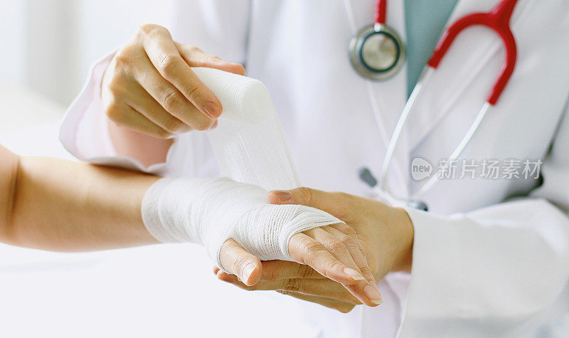 女医生用听诊器包扎病人的手的特写。