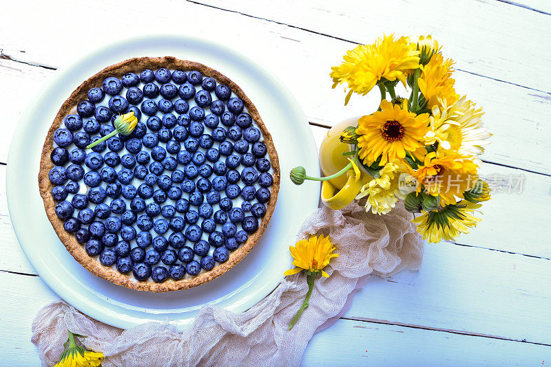 蛋糕和浆果。白色的乡村餐桌上放着夏天盛开的蓝莓派。蓝莓。早餐和早餐概念