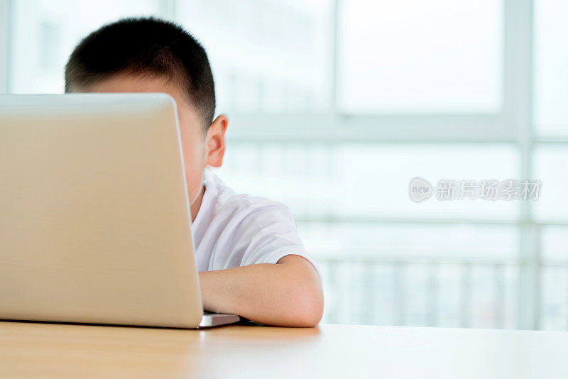 年轻的亚洲男孩在室内用笔记本电脑