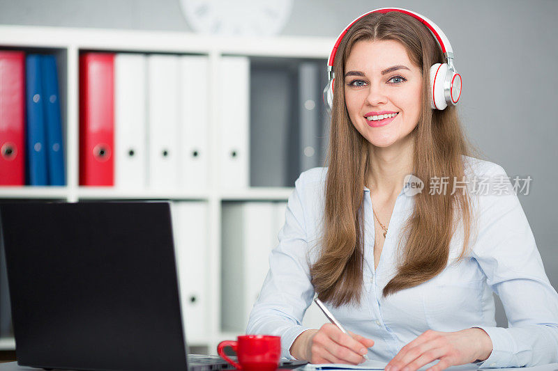 美丽的女学生戴着耳机听音乐和学习。
