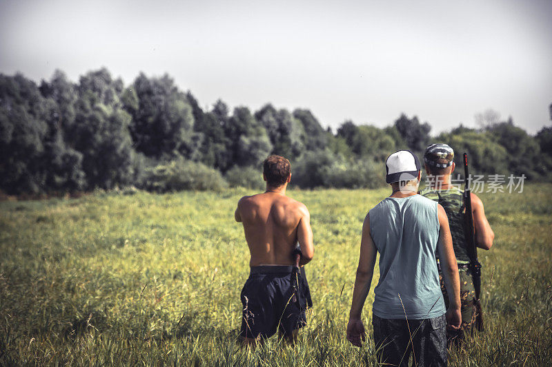 在狩猎季节，一群强壮的猎人穿过长满高草的乡村田野