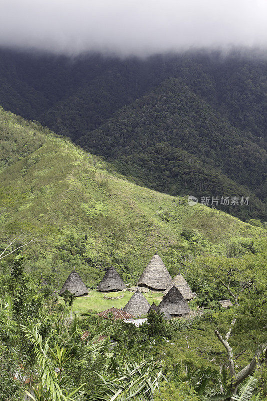 远处韦热波传统村落的风景写真。山中空地上的一小群小屋，背景是山脊线和云彩