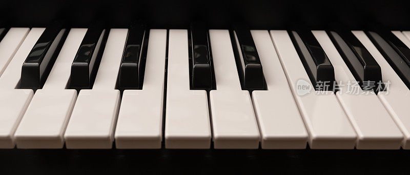 经典的大钢琴键盘与光滑的黑白键作为一个全景横幅格式的音乐背景