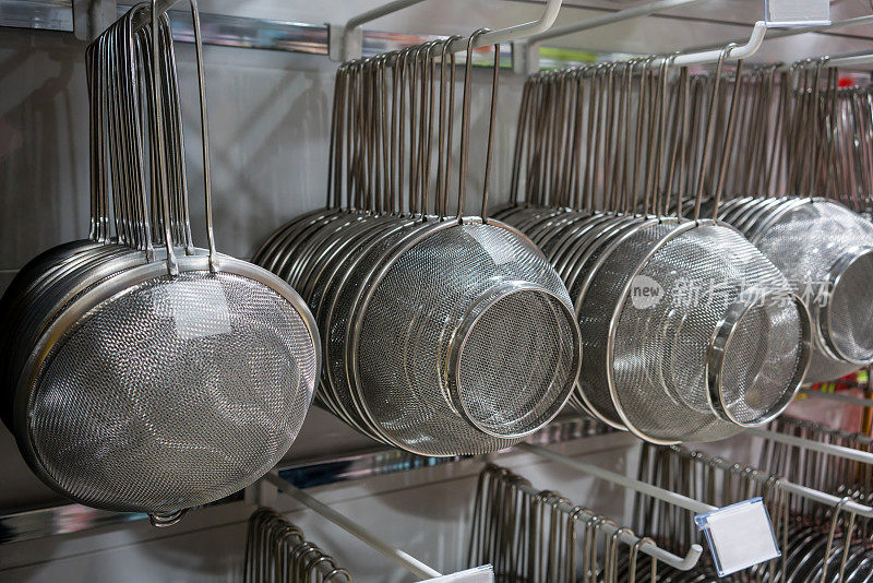 在批发商店的金属架子上挂着许多排银色的金属过滤器和滤网。